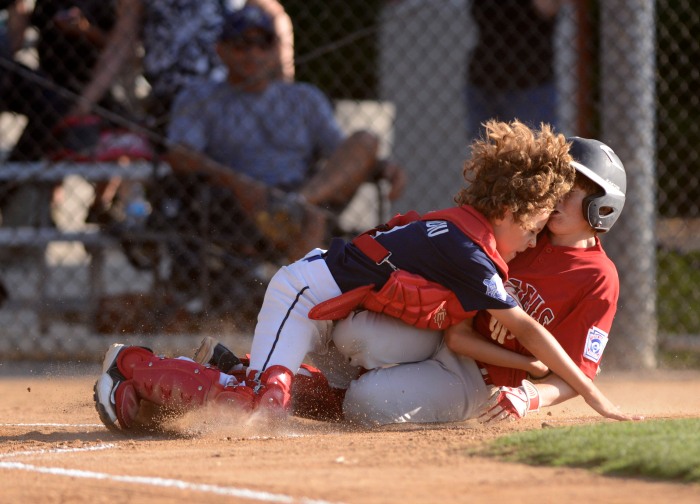 San Juan Capistrano's Hayden Dendiu, left, and Rancho Santa Margarita's Aiden Armstrong crash into each other as the Angel's score their first run of the game during the District 68 Minor tournament Thursday at Rancho Santa Margarita Little League. – 6/06/13 – MICHAEL LOPEZ, ORANGE COUNTY REGISTER –  